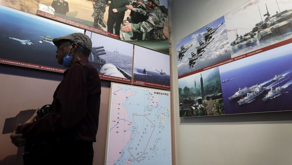 In this July 27, 2017 photo, a man walks by photos showing a map of East China Sea and Chinese military activities at East China Sea on display at the military museum in Beijing - Sputnik International