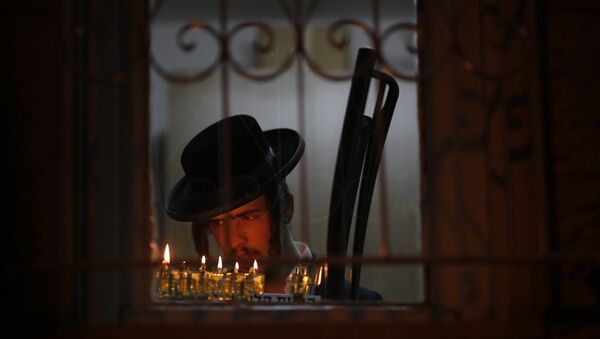 An ultra-Orthodox Jewish man lights candles during the Jewish holiday of Hanukkah in Jerusalem's Mea Shearim neighborhood in Jerusalem, Sunday, Dec. 17, 2017 - Sputnik International