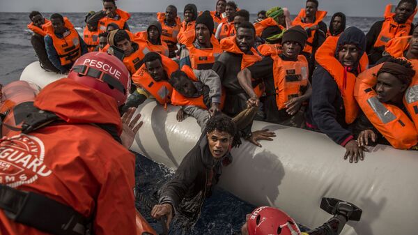 Спасение мигрантов сотрудниками испанской общественной организации Proactiva Open Arms с переполненной резиновой лодки у берегов Ливии - Sputnik International