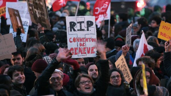 A protester holds a placard reading RIP Geneva convention in Paris on February 21, 2018, during a demonstration against the French government's new immigration bill - Sputnik International