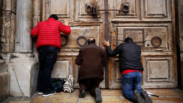 Worshippers kneel and pray in front of the closed doors of the Church of the Holy Sepulchre in Jerusalem's Old City, February 25, 2018 - Sputnik International