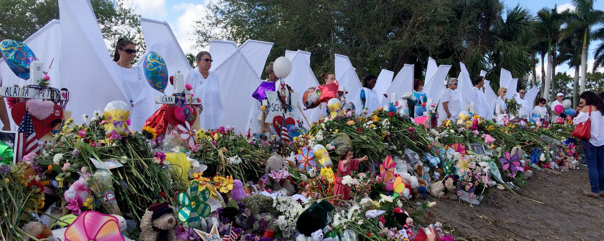 Seventeen people dressed as angels stand Sunday, Feb. 25, 2018, at the memorial outside Marjory Stoneman Douglas High School in Parkland, Fla., for those killed in a shooting on Feb. 14.  - Sputnik International, 1920, 15.02.2023