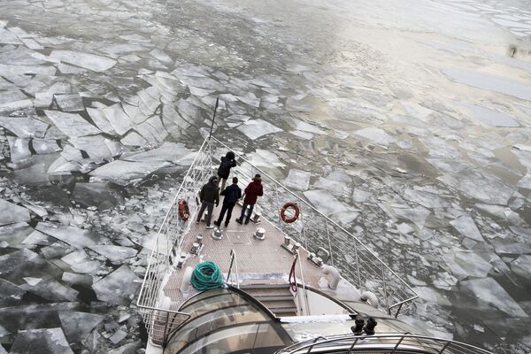 Passengers stand on a deck of a  tourist boat with restaurant aboard especially designed for winter river cruises as it breaks through the frozen Moskva River in Moscow, Russia, Monday, - Sputnik International