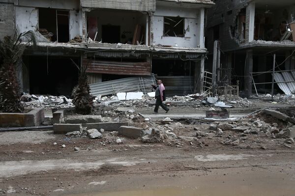 A Syrian man walks past destroyed buildings in the rebel-held town of Haza, in the besieged Eastern Ghouta region on the outskirts of the capital Damascus - Sputnik International