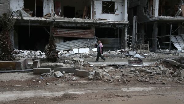 A Syrian man walks past destroyed buildings in the rebel-held town of Haza, in the besieged Eastern Ghouta region on the outskirts of the capital Damascus - Sputnik International