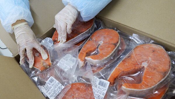 A worker at the Russian Fish Factory fish processing plant puts finished product in the box on the packaging line - Sputnik International