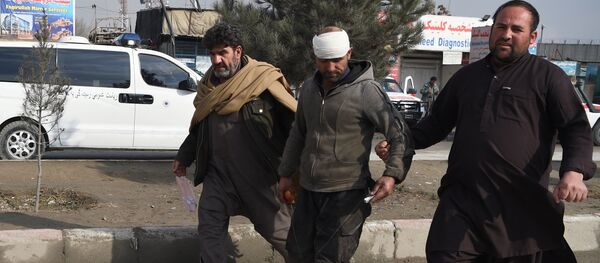 An Afghan resident assists an injured man near the site of a suicide car bomb attack targeting foreign troops in Kabul on March 2, 2018 - Sputnik International