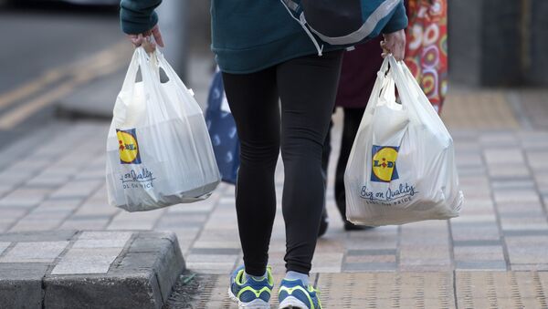 A person leaves with their goods in plastic carrier bags after shopping at a branch of Lidl in south London on January 10, 2018 - Sputnik International
