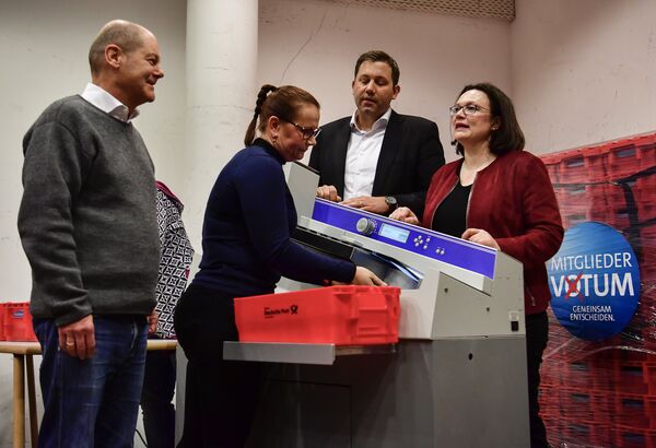 Acting Chairman of the Social Democratic Party (SPD) Olaf Scholz (L), Secretary-General of the Social Democratic Party (SPD) Lars Klingbeil (2nd R) and German Labour and Social Minister Andrea Nahles (R) react as they look at an envelope opening machine prior to the counting of the ballots, at the headquarters of Germany's social democratic SPD party in Berlin on March 3, 2018, as SPD members voted on whether or not to join a new coalition government with German Chancellor Angela Merkel's conservatives - Sputnik International