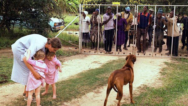 In this file photo dated March 29, 2000, Pippa van Rechteren, left, and her two-year-old twins Catherine, second from left, and Elisabeth, third from left, are blocked from leaving their house on the white-owned commercial farm, Chiripiro, by Zimbabwe war veterans in Centenary district, 150 kilometers (93 miles) north of Harare - Sputnik International