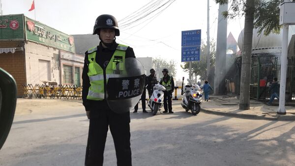 (File) In this Nov. 2, 2017 photo, a police personnel holding shield and baton guards a security post leading into a center believed to be used for re-education in Korla in western China's Xinjiang region - Sputnik International
