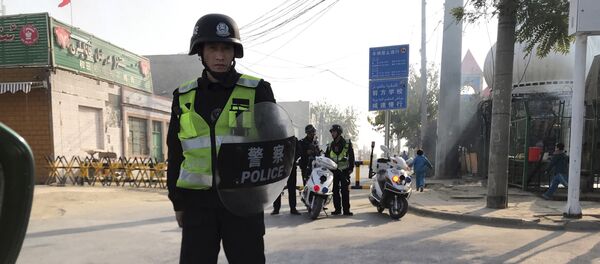 (File) In this Nov. 2, 2017 photo, a police personnel holding shield and baton guards a security post leading into a center believed to be used for re-education in Korla in western China's Xinjiang region - Sputnik International