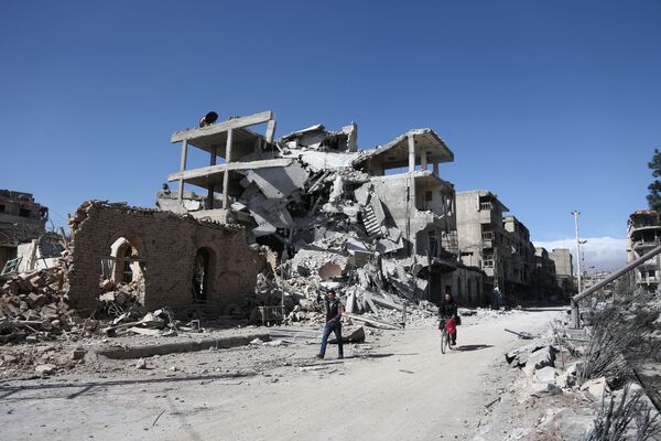 Syrians walk past destroyed buildings in the rebel-held town of Hamouria, in the besieged Eastern Ghouta region on the outskirts of the capital Damascus, on March 9, 2018 Syrians walk past destroyed buildings in the rebel-held town of Hamouria, in the besieged Eastern Ghouta region on the outskirts of the capital Damascus, on March 9, 2018 - Sputnik International