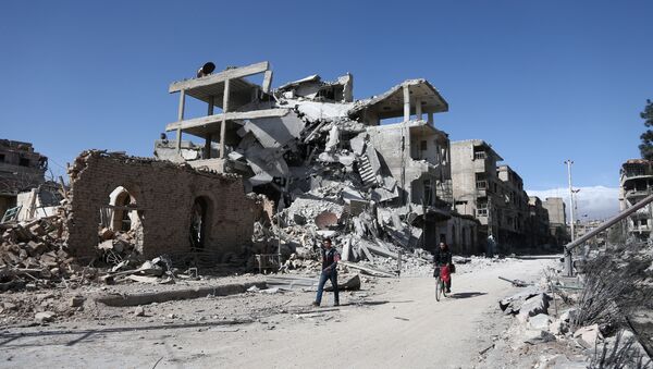 Syrians walk past destroyed buildings in the rebel-held town of Hamouria, in the besieged Eastern Ghouta region on the outskirts of the capital Damascus, on March 9, 2018 - Sputnik International