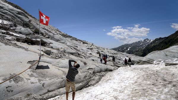 A tourist takes a picture of a Swiss flag on the Rhone Glacier covered with insulating foam to be protected from the sun on July 14, 2015, near Gletsch - Sputnik International