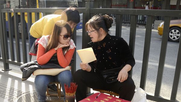 (File) A fortune-teller talks with two girls by a road in Beijing on October 24, 2012 - Sputnik International