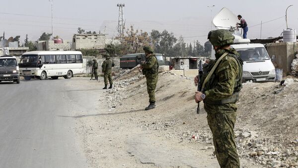Russian military police members stand guard at the Wafideen checkpoint on the outskirts of the Syrian capital Damascus neighbouring the rebel-held Eastern Ghouta enclave on March 13, 2018, awaiting any civilians evacuating from the area - Sputnik International