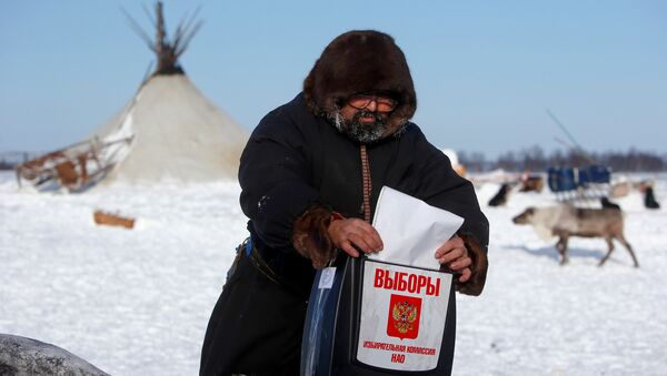A herder of the agricultural cooperative organisation Harp casts his vote into a mobile ballot box during the early voting in remote areas ahead of the presidential election, at a reindeer camping ground, about 250 km south of Naryan-Mar, in Nenets Autonomous District, Russia, March 4, 2018 - Sputnik International