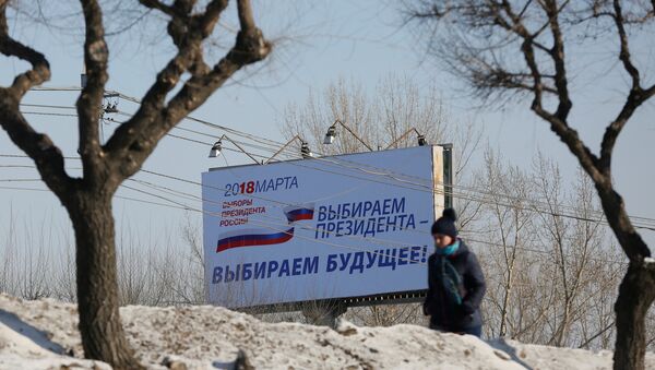 A woman walks past a billboard advertising the upcoming presidential election, in Krasnoyarsk, Russia March 11, 2018 - Sputnik International