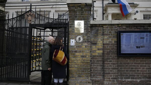 Two people wait to get into the Russian Embassy as a man works to untangle the national flag flown from the Russian Embassy, after it became entangled on its staff at the embassy in London, Wednesday, March 14, 2018 - Sputnik International