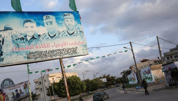 A Palestinian vehicle drives through a roundabout past a billboard bearing the portraits of Mohammed Abu Shamala (R) and Raed al-Attar (C), commanders of Hamas' armed wing al-Qassam Brigades, in Rafah in the southern Gaza Strip on January 19, 2018 - Sputnik International