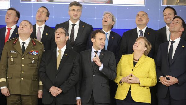 French President Emmanuel Macron, front center, speaks with German Chancellor Angela Merkel, front second right, as they look up at a drone flying above their heads during a group photo at an EU summit at the Europa building in Brussels on Thursday, Dec. 14, 2017 - Sputnik International