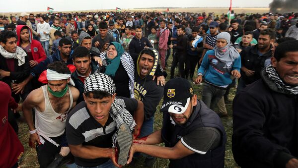A wounded Palestinian woman is evacuated during clashes with Israeli troops, during a tent city protest along the Israel border with Gaza, demanding the right to return to their homeland, the southern Gaza Strip - Sputnik International