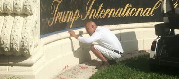 A worker cleans up red paint from the stone sign at the entrance to the Trump International Golf Club in West Palm Beach, Fla., Sunday, April 1, 2018. A worker cleans up red paint from the stone sign at the entrance to the Trump International Golf Club in West Palm Beach, Fla., Sunday, April 1, 2018. - Sputnik International