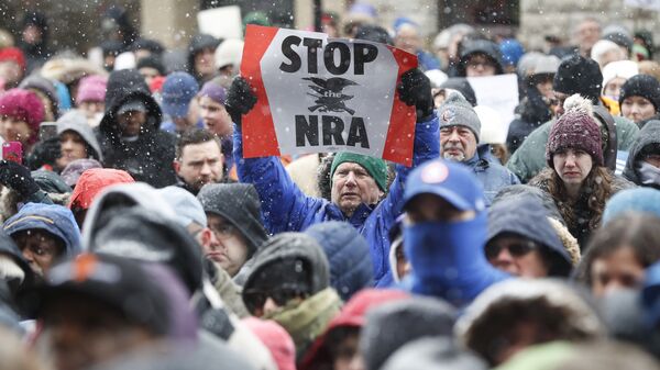 A demonstrator holds a STOP the NRA sign outside city hall during the March for Our Lives protest for gun legislation and school safety, Saturday, March 24, 2018 - Sputnik International