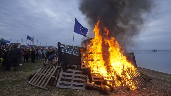 The remains of a small boat flying European flags is burnt on a bonfire during a demonstration in Whitstable, southeast England on April 8, 2018 against the Brexit transition deal that would see Britain continue to adhere to the Common Fisheries Policy after formally leaving the EU - Sputnik International