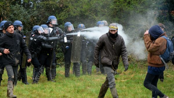 Anti-riot policemen spray tear gas during clashes with protestors protecting the place named Les 100 noms in the ZAD (Zone a Defendre - Zone to defend) in Notre-Dame-des-Landes, western France, on April 9, 2018, during a huge security operation to clear a rural protest camp at the site of an abandoned airport project - Sputnik International