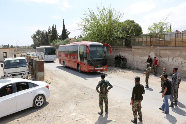 Pro-Syrian government forces gather around busses carrying Jaish al-Islam fighters and their families from their former rebel bastion of Douma as they arrive at the Syrian government-held side of the Wafideen checkpoint on the outskirts of Damascus, after being evacuated from the last rebel-held pocket in Estearn Ghouta on April 9, 2018 - Sputnik International