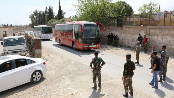 Pro-Syrian government forces gather around busses carrying Jaish al-Islam fighters and their families from their former rebel bastion of Douma as they arrive at the Syrian government-held side of the Wafideen checkpoint on the outskirts of Damascus, after being evacuated from the last rebel-held pocket in Estearn Ghouta on April 9, 2018 - Sputnik International