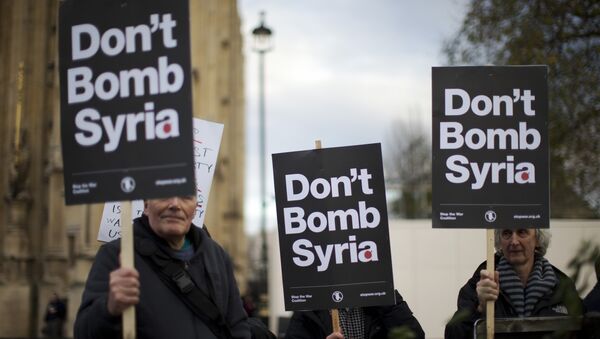 Supporters of the Stop the War Coalition hold placards protesting against Britain launching airstrikes against Islamic State extremists inside Syria, outside the Houses of Parliament as a debate goes on before a vote, Wednesday, Dec. 2, 2015. - Sputnik International