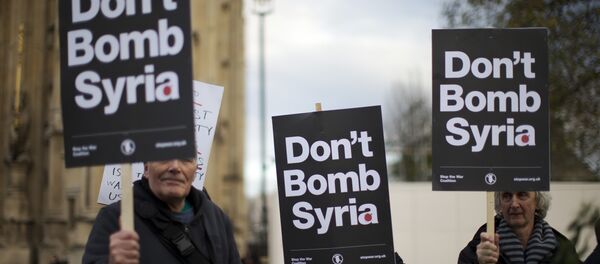 Supporters of the Stop the War Coalition hold placards protesting against Britain launching airstrikes against Islamic State extremists inside Syria, outside the Houses of Parliament as a debate goes on before a vote, Wednesday, Dec. 2, 2015. - Sputnik International