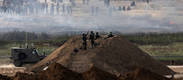 Israeli soldiers are seen next to the border fence on the Israeli side of the Israel-Gaza border, as Palestinians protest on the Gaza side of the border, Israel April 5, 2018 - Sputnik International