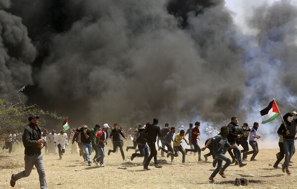 Palestinian protesters run to cover from teargas fired by Israeli soldiers during clashes with Israeli troops along Gaza's border with Israel, east of Khan Younis, Gaza Strip, Friday, April 6, 2018 Palestinian protesters run to cover from teargas fired by Israeli soldiers during clashes with Israeli troops along Gaza's border with Israel, east of Khan Younis, Gaza Strip, Friday, April 6, 2018 - Sputnik International