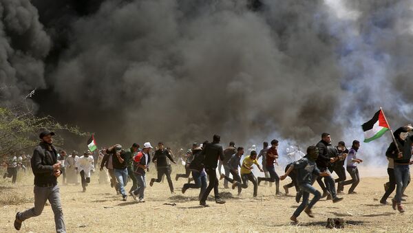 Palestinian protesters run to cover from teargas fired by Israeli soldiers during clashes with Israeli troops along Gaza's border with Israel, east of Khan Younis, Gaza Strip, Friday, April 6, 2018 - Sputnik International