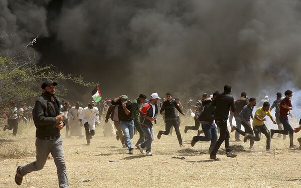 Palestinian protesters run to cover from teargas fired by Israeli soldiers during clashes with Israeli troops along Gaza's border with Israel, east of Khan Younis, Gaza Strip, Friday, April 6, 2018 - Sputnik International