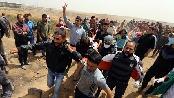A wounded Palestinian is evacuated during clashes with Israeli troops at a protest demanding the right to return to their homeland, at the Israel-Gaza border, east of Gaza City, April 13, 2018 - Sputnik International