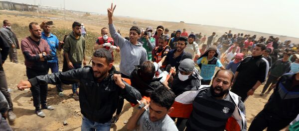 A wounded Palestinian is evacuated during clashes with Israeli troops at a protest demanding the right to return to their homeland, at the Israel-Gaza border, east of Gaza City, April 13, 2018 - Sputnik International