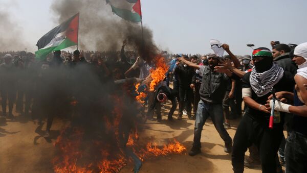 Palestinian demonstrators burn an Israeli flag during a protest demanding the right to return to their homeland, at the Israel-Gaza border, in the southern Gaza Strip, April 13, 2018 - Sputnik International