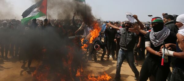 Palestinian demonstrators burn an Israeli flag during a protest demanding the right to return to their homeland, at the Israel-Gaza border, in the southern Gaza Strip, April 13, 2018 - Sputnik International