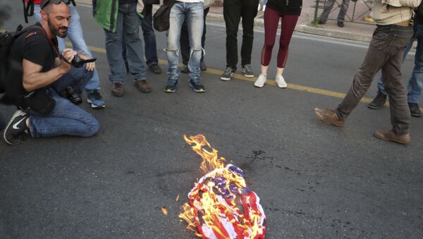 Protesters burn an American flag outside the U.S. Embassy in Athens, Friday, April 13, 2018, during a rally against possible western military intervention in Syria - Sputnik International
