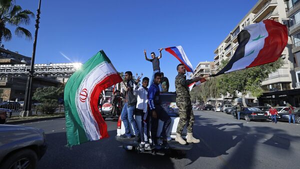 Syrian government supporters wave Syrian, Iranian and Russian flags as they chant slogans against U.S. President Trump during demonstrations following a wave of U.S., British and French military strikes to punish President Bashar Assad for suspected chemical attack against civilians, in Damascus, Syria, Saturday, April 14, 2018 - Sputnik International