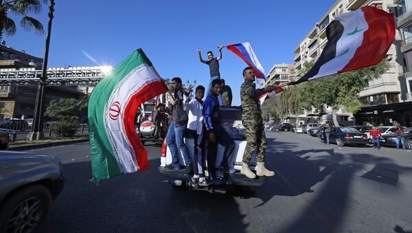 Syrian government supporters wave Syrian, Iranian and Russian flags as they chant slogans against US President Trump during demonstrations following a wave of US, British and French military strikes to punish President Bashar Assad for suspected chemical attack against civilians, in Damascus, Syria, Saturday, April 14, 2018. - Sputnik International