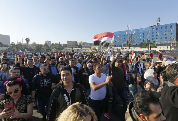 Syrians wave the national flag and wave portraits of President Bashar al-Assad as they gather at the Umayyad Square in Damascus on April 14, 2018, to condemn the strikes carried out by the United States, Britain and France against the Syrian regime Syrians wave the national flag and wave portraits of President Bashar al-Assad as they gather at the Umayyad Square in Damascus on April 14, 2018, to condemn the strikes carried out by the United States, Britain and France against the Syrian regime - Sputnik International