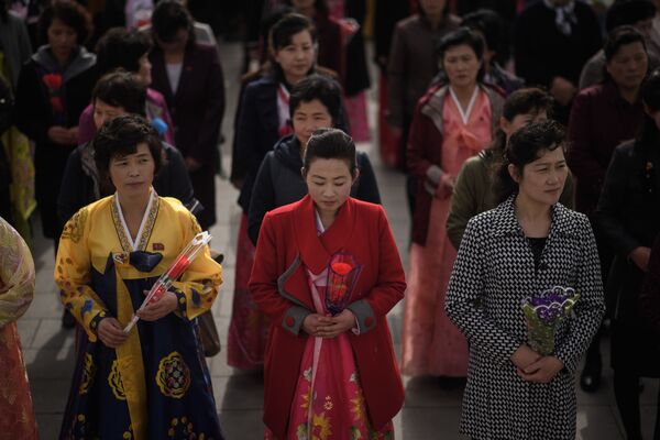 Women holding flowers arrive to pay their respects before the statues of late North Korean leaders Kim Il Sung and Kim Jong Il, - Sputnik International