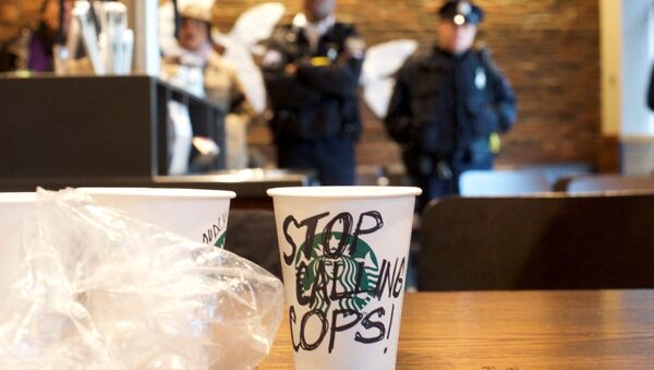 A Starbucks coffee cup with Stop Calling Cops! written on the side sits on a table as police monitor protestors demonstrating inside a Center City Starbucks, where two black men were arrested, in Philadelphia, Pennsylvania U.S., April 16, 2018. - Sputnik International