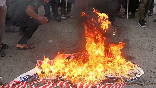 Protesters burn representations of US flags during a protest against the US-led missile attack on Syria, in Tahrir Square, Baghdad, Iraq, Sunday, April 15, 2018. - Sputnik International